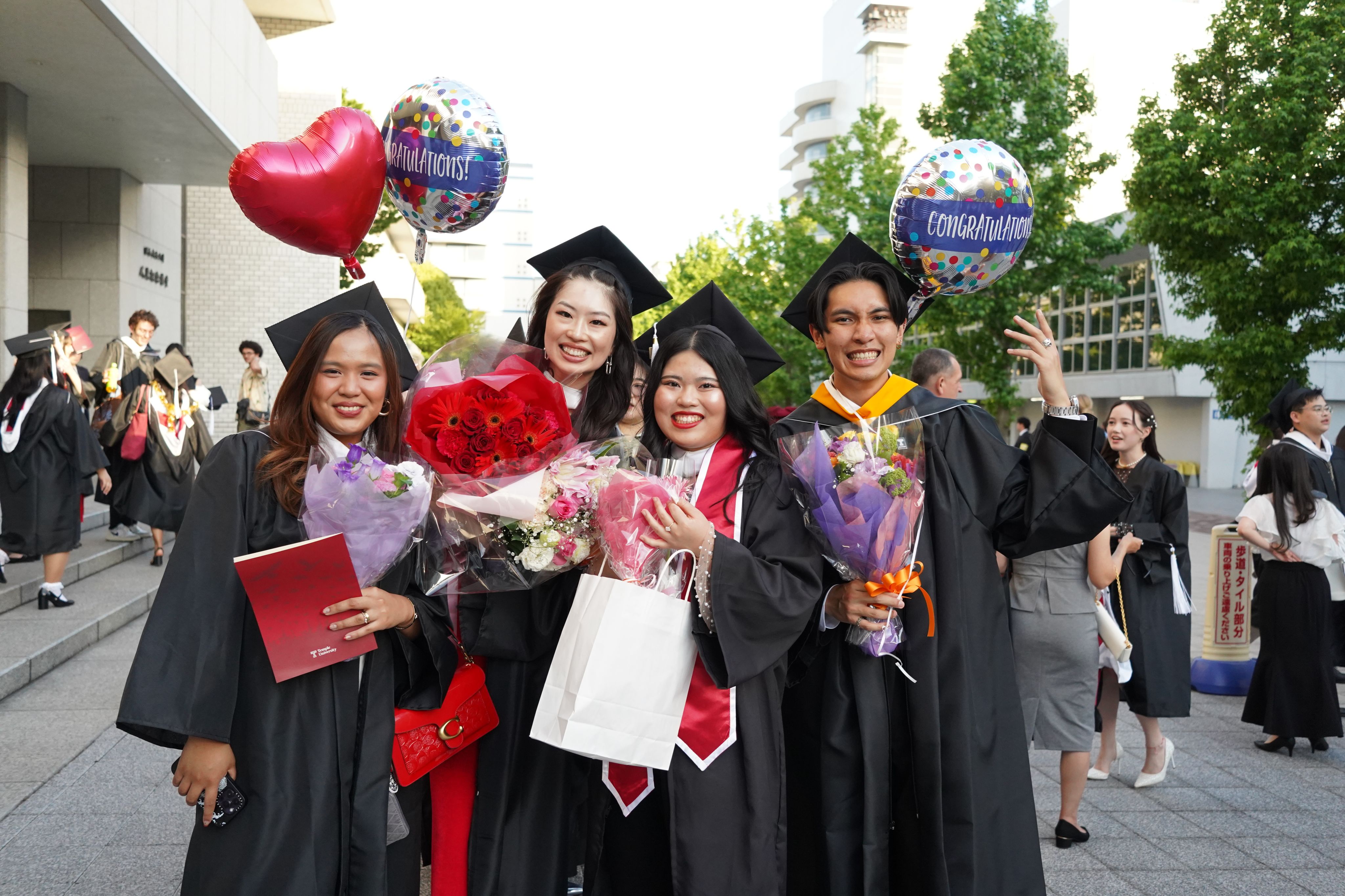 Graduates taking a picture in front of the Hitomi Hall