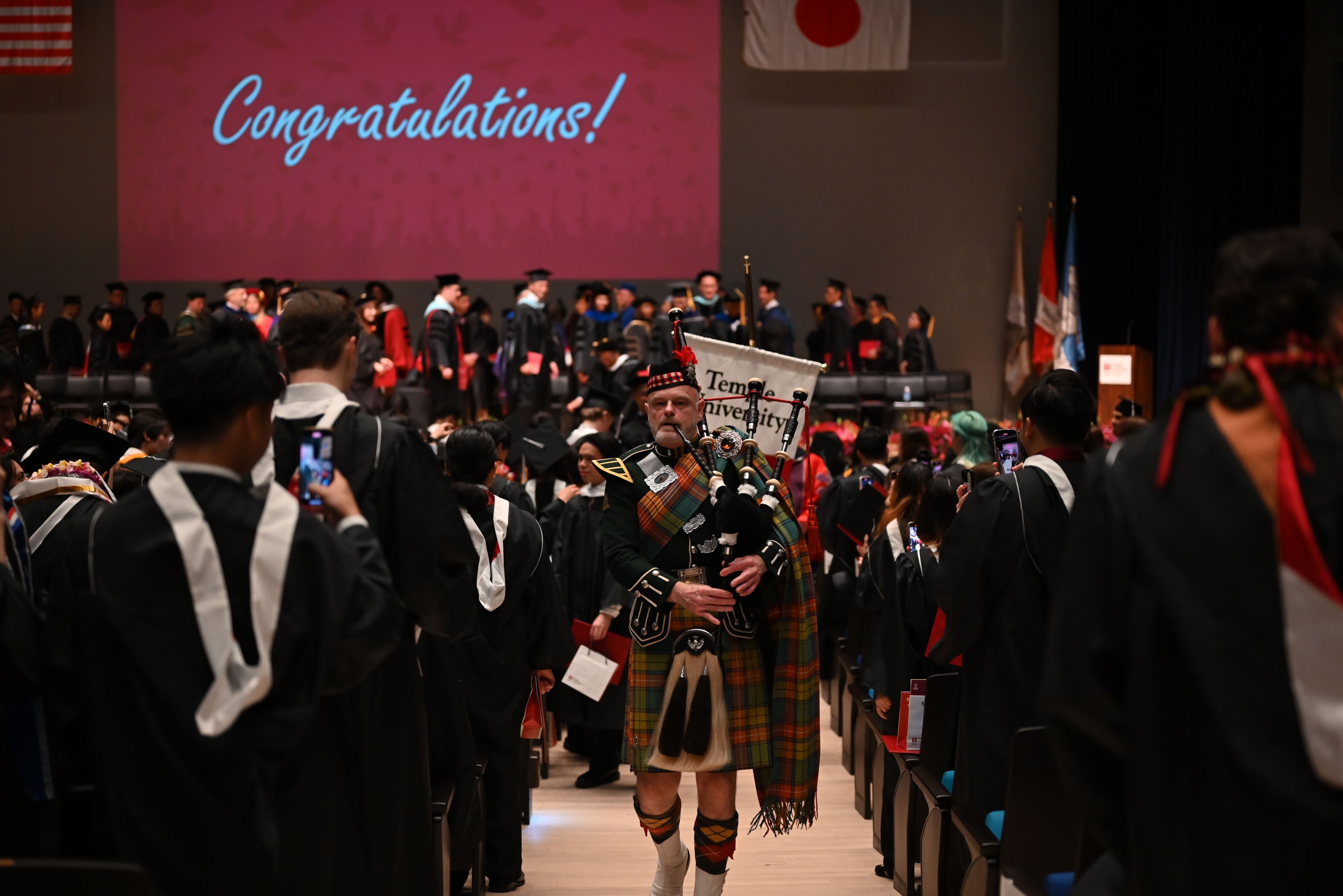 The bagpiper and stage party walk out from the stage.