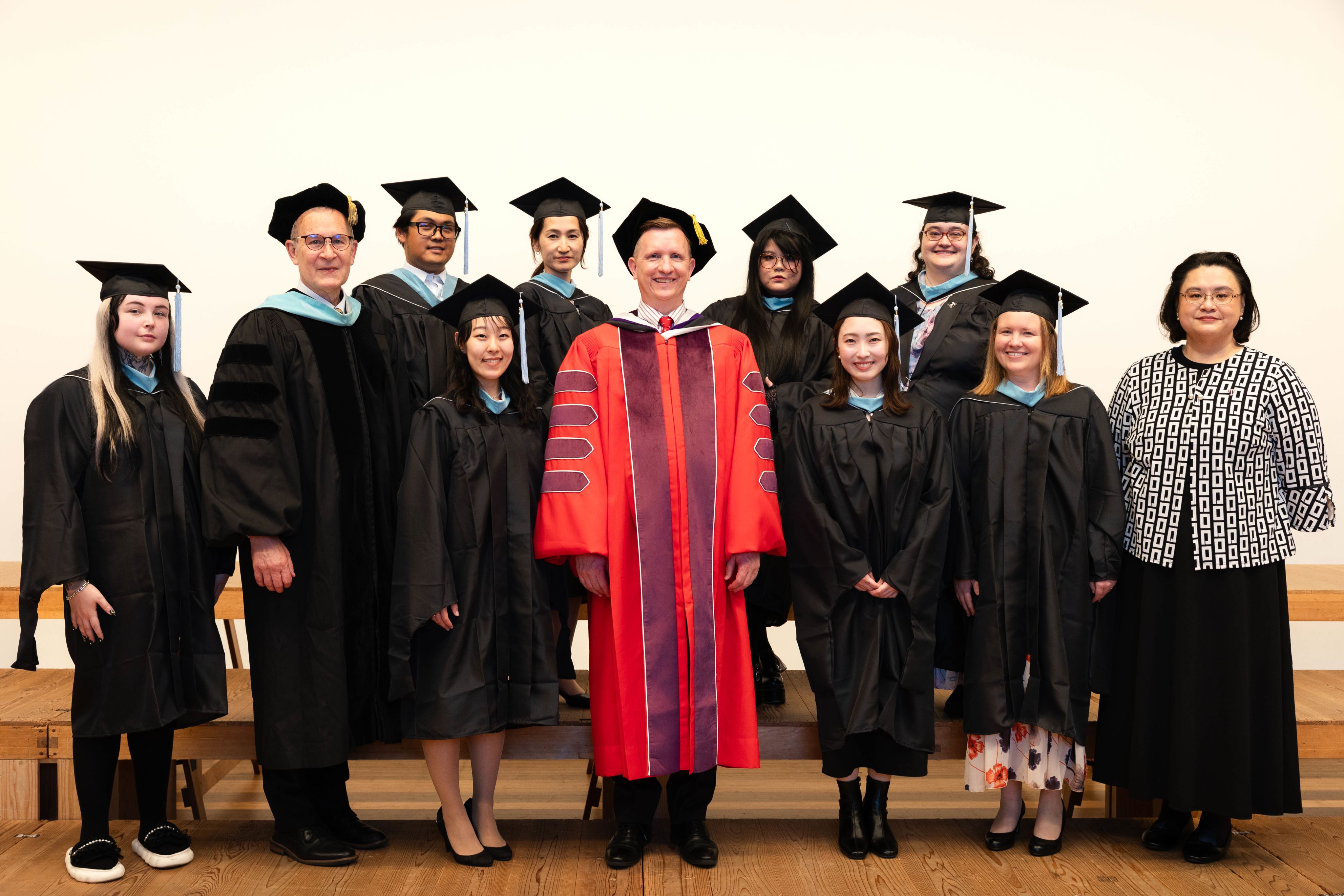 Graduates from the Graduate College of Education smiling and posing for a group photo in their caps and gowns.