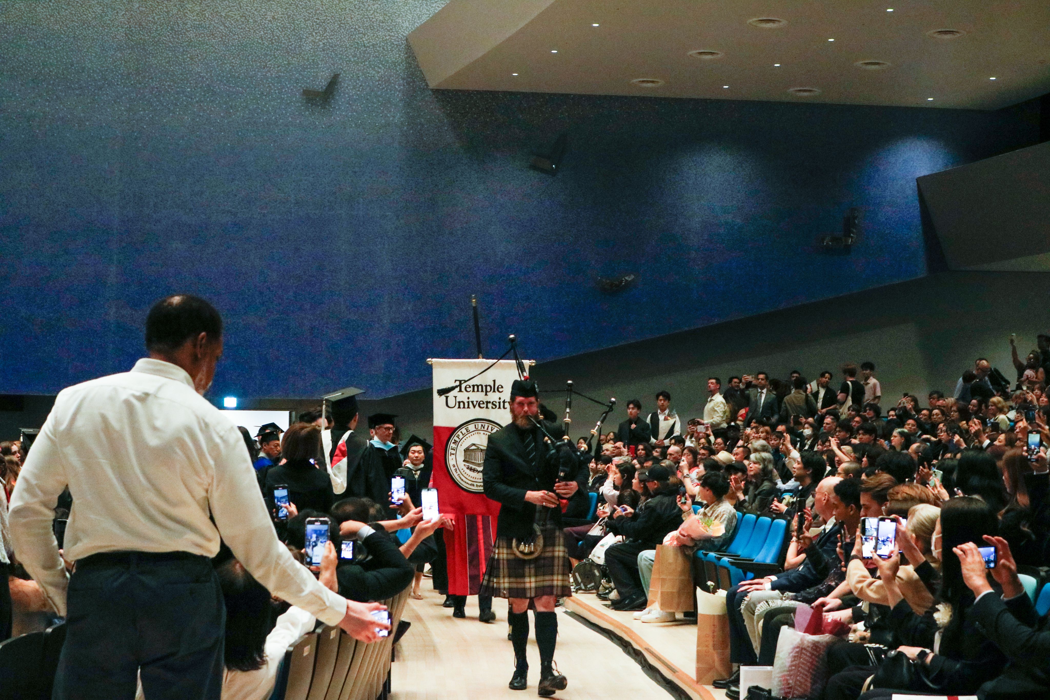 The bagpiper and stage party walk out from the stage.